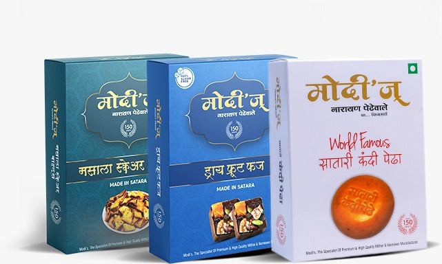Three boxes of Modi’s Narayan Pedhewale sweets are displayed, featuring Masala Slices, Dry Fruit Fudge, and a white box with Wolf Famous Satari Kandi Pedha, all labeled Made in Satara.